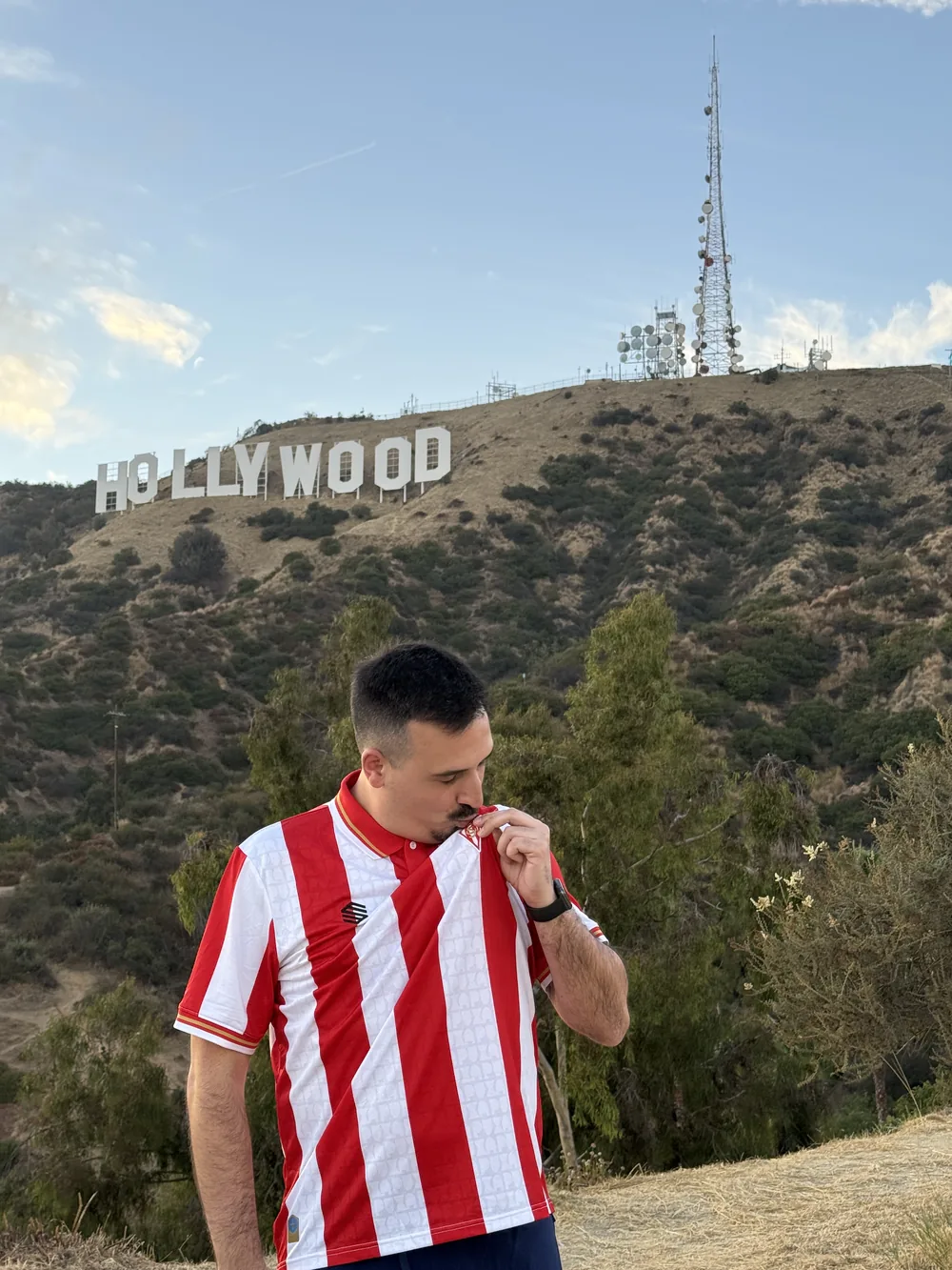 Elopi23 besando el escudo del Sporting con la nueva camiseta 2026/27 ante el cartel de Hollywood