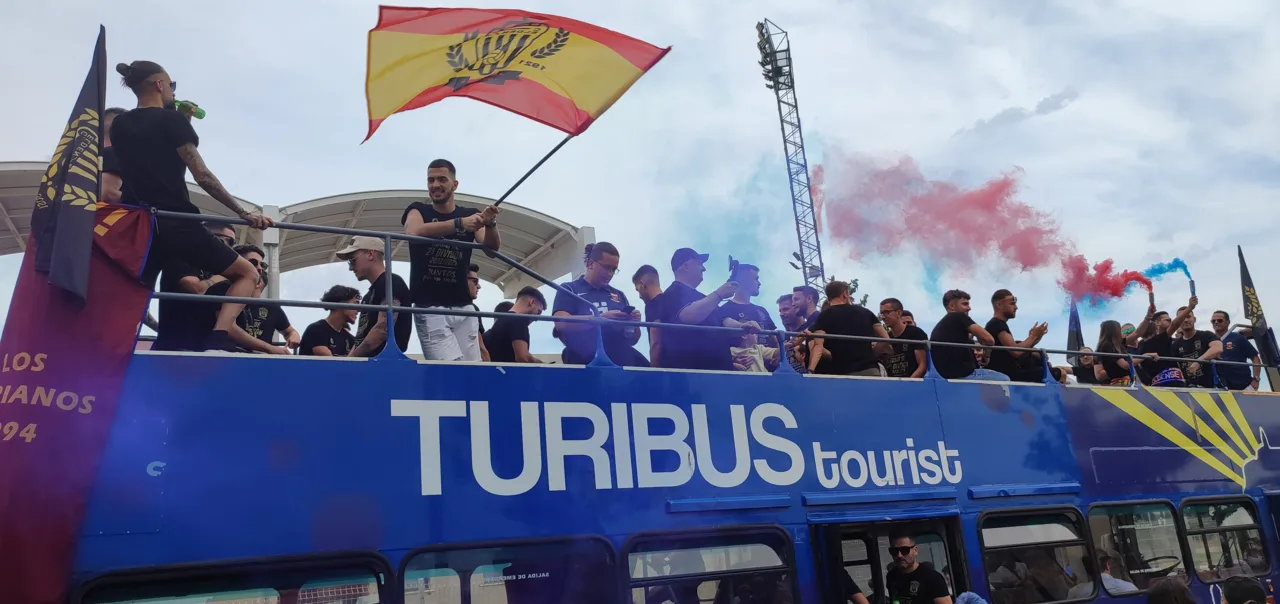 Jugadores del CD Eldense celebrando en un autobús descubierto con bengalas azulgranas