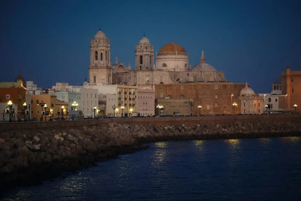 La catedral de Cádiz iluminada al anochecer, junto al Campo del Sur